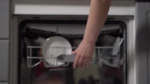 Woman Loading Dishes Into Kitchen Dishwasher