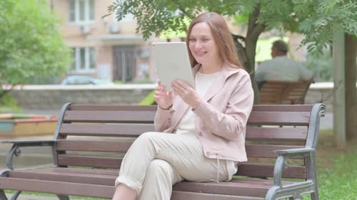 Modern Old Woman Doing Video Chat on Tablet Outdoor