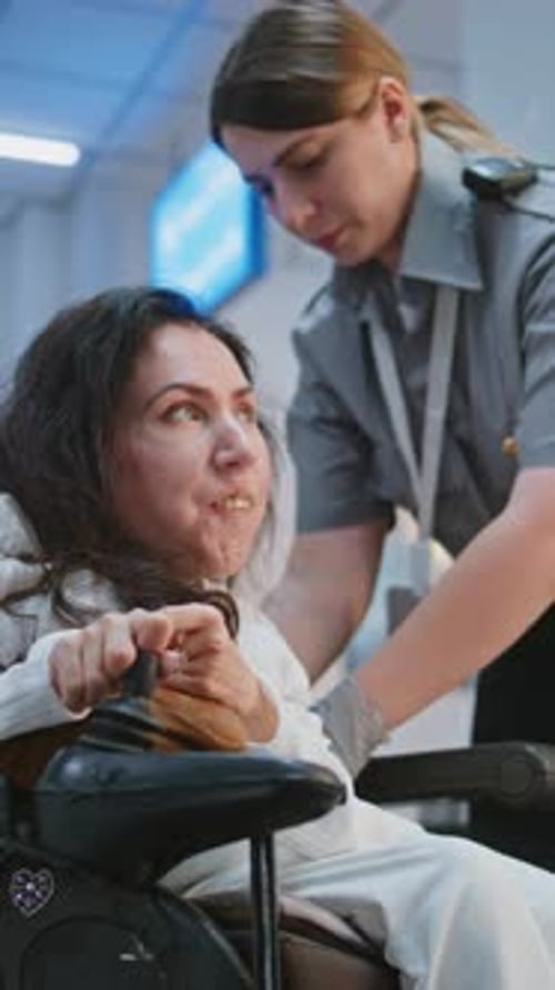 Female TSA Officer Checking Woman with Physical Disability in Airport Terminal