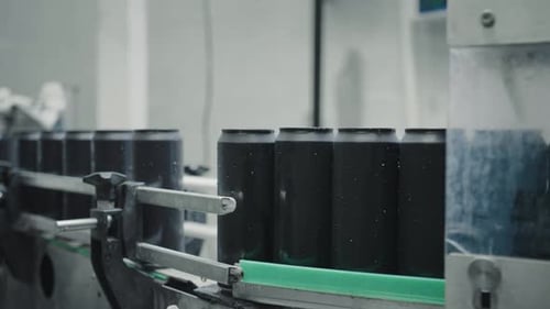 Black aluminum cans moving on conveyor belt in beverage factory