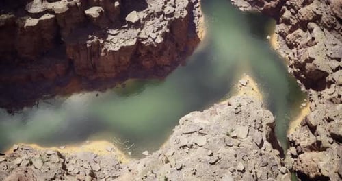 Desert River Winding Through Rocky Canyon Landscape Under Bright Sunlight