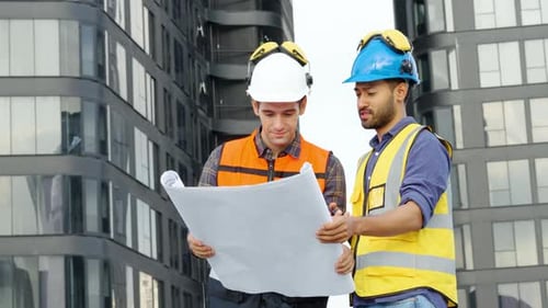 Zwei Bauingenieure überprüfen die Informationen aus dem Bauplan in Teamarbeit, Projektleiter planen