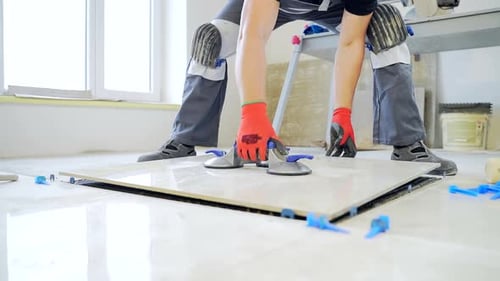 industrial tiler Professional builder worker installing floor a large ceramic tile at repair renovat