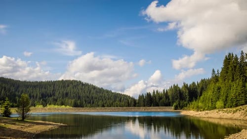Lago con aguas cristalinas y costa de piedra en un bosque de abetos con abetos contra un cielo diurno