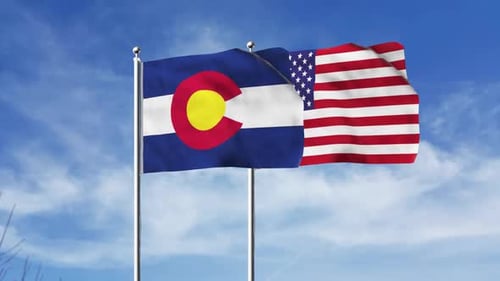 Waving Colorado and USA Flags Against Blue Sky