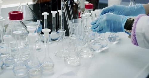 Lab Technician Working with Glass Beakers and Cylinders
