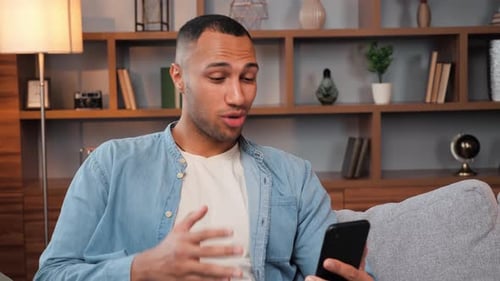 Smiling Man Video Calling on Smartphone While Relaxing