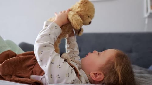 Adorable Toddler Girl Playing with Teddy Bear on Bed