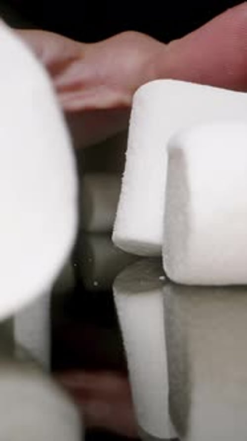 Vertical video. Hand Greedily Gathers Many Marshmallows from the Table and Disappears into Darkness,