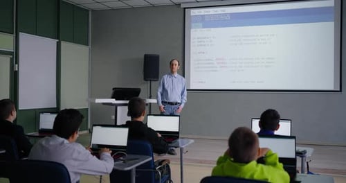 Erwachsener Mann, der Schülern das Programmieren und Codieren beibringt, Teenager, Jungen, die ihm zuhören, optionaler Unterricht