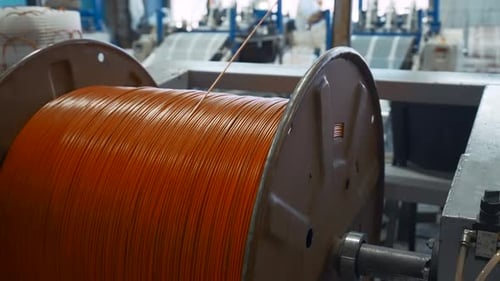 Unwinding Orange Cable on Large Spool at Factory