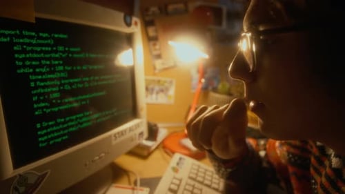 Entwickler der Generation Y mit Brille beim Lesen von Programmcode auf einem alten Computer in den 90ern