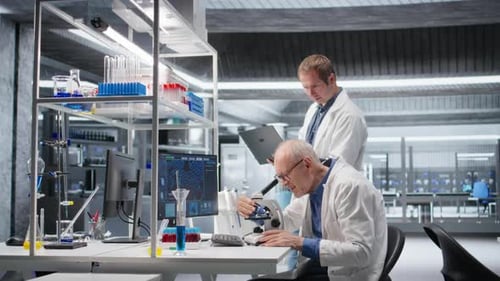 Senior Chemist and Coworker Observing Specimen Under Microscope