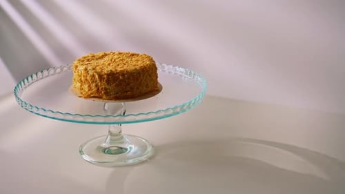 Freshly prepared delicious Napoleon cake from puff pastry on a transparent stand on a white