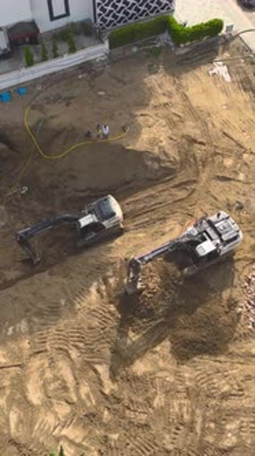 Vertical Video Heavy Machinery Operates at Full Power on a Busy Construction Site Lifting and Moving