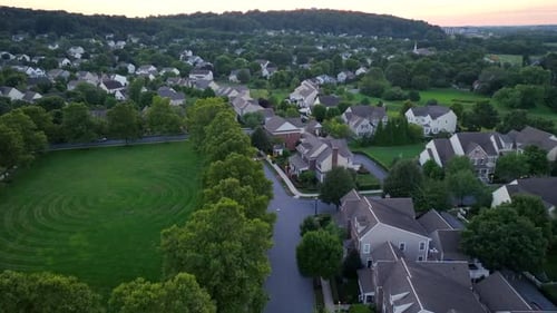 Grünes Grasfeld des Parks in einem Wohngebiet in einem amerikanischen Vorort bei Sonnenuntergang. Idyllische Landschaft mit Rot