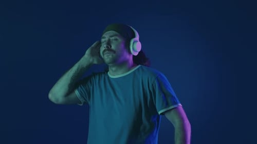 A Man Wearing White Wireless Headphones Listens to Music and Dances Vigorously A Man in a Studio on