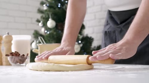 Hands Rolling Dough in Festive Christmas Kitchen