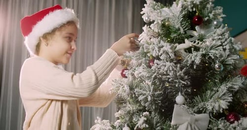 Girl Decorating Christmas Tree with Ornament at Home