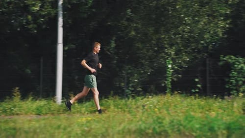 Young Adult Running Through Green Park on Sunny Day