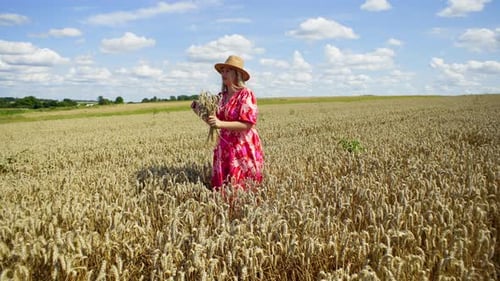 Caucasian Girl in a Dress Dancing in a Wheat Field