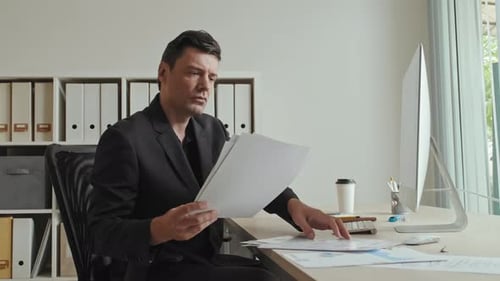 Man Working in Office at Computer Looking Stressed