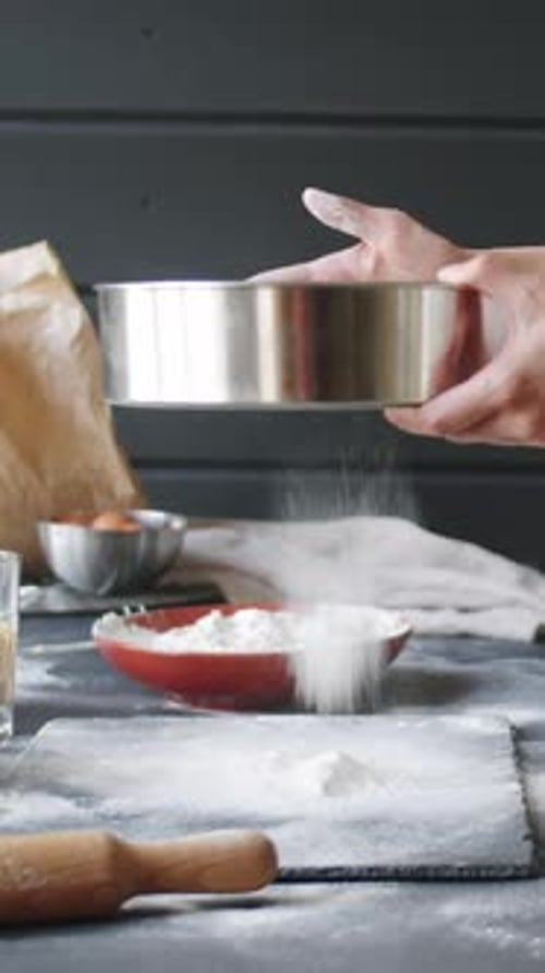Person Sifting Flour to Make Dough in Kitchen