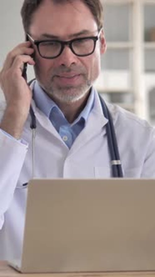 Doctor on Phone with Laptop, Indoor Setting