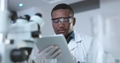Science, research and digital tablet by black man scientist in a laboratory for healthcare