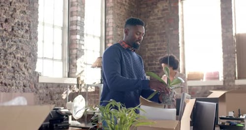 Diverse colleagues unpacking boxes with documents and office items in creative office in slow motion