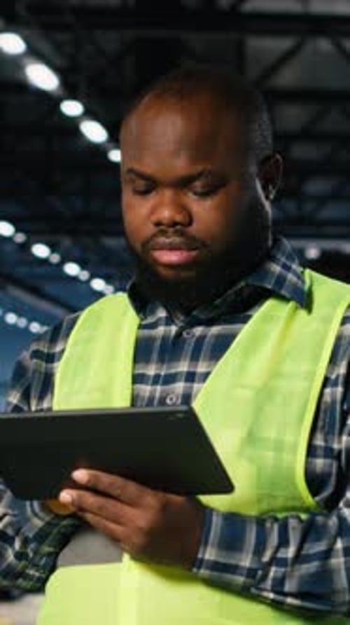 Vidéo verticale Le superviseur de l'usine vérifie l'équipement d'assemblage sur une tablette dans une usine de fabrication