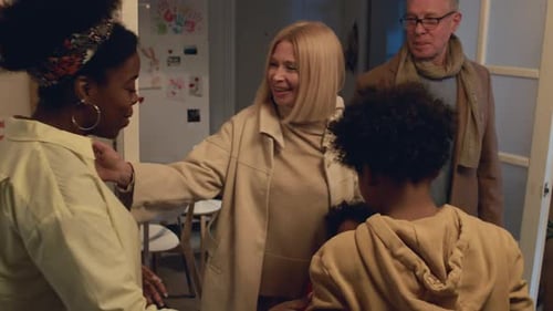 Family Welcoming Guests Home with Hugs and Gifts