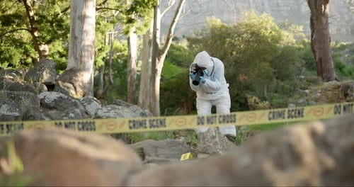 Forensic, photographer and evidence at crime scene for investigation in forest with police tape