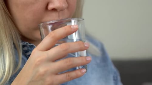 Woman Taking Pill with Glass of Water, Close Up