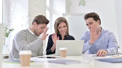 Cheerful Creative Woman doing Video Chat on Laptop in Office