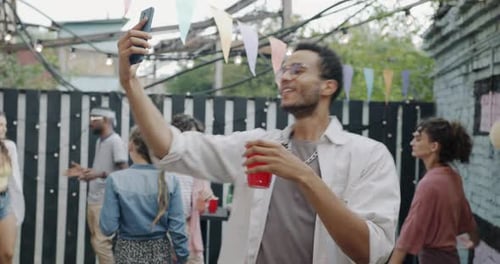 Young Man Video Calling Friends at Cheerful Outdoor Party