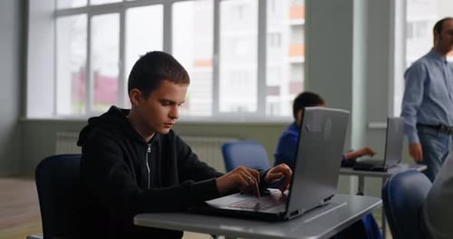 Smart Boys Students In Classroom Pupils Working With Laptops Ad Teacher Walking In Room