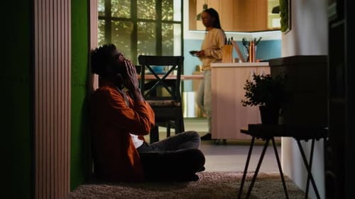 Jeune adulte afro-américain bouleversé et insatisfait assis sur le sol