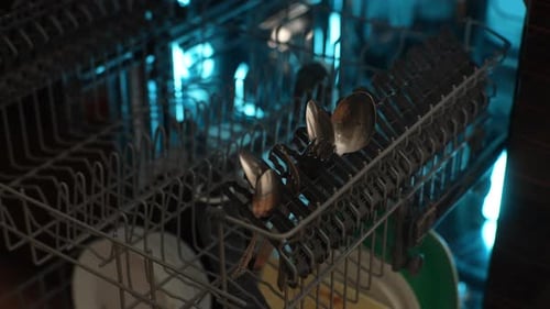 Closeup Cropped Shot of Unrecognizable Man Loading Backlit Dishwasher Machine with Dirty Stainless