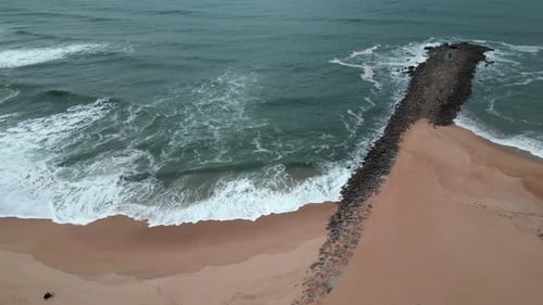 Aerial view of the ocean and the waves reaching the beach.