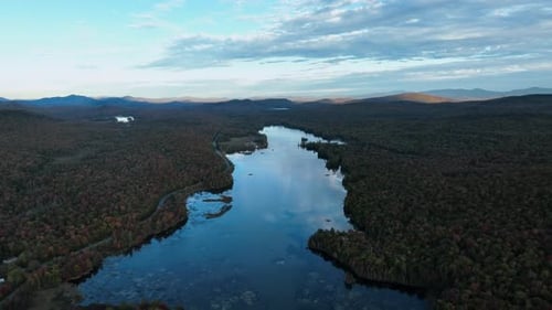 A Lake Embraced by the Vibrant Autumnal Shades of the Surrounding Foliage - Aerial Pullback