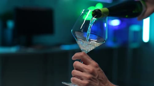 Pouring White Wine into a Glass Under Neon Lights