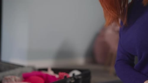 Redhaired Female Traveler Puts Clothes Into Suitcase