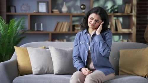 Woman on Sofa Experiencing Ear Pain