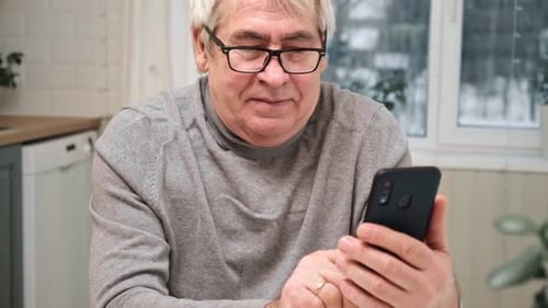 Mature Adult Using Smartphone in Home Interior