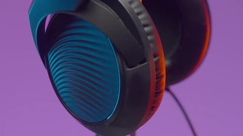 Modern Wireless Headphones Rotating on Stand with Purple Background