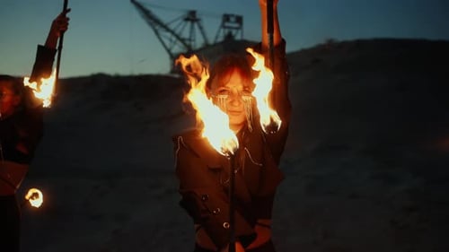 Attraktive Frauen tanzen mit brennenden Fackeln und schauen in die Kamera Fantastische Feuerleistung