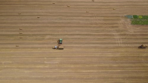 Tractor Harvesting Hay Bales in Field Aerial