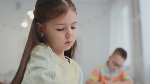 Child Drawing with Crayons in School Classroom