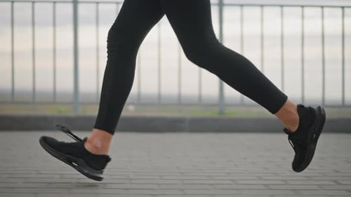 Woman Jogging in Black Leggings and Sneakers on Outdoor Track By River